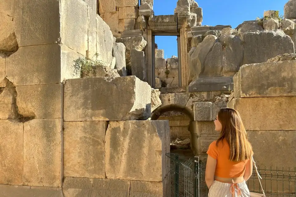 A visitor admires the detailed stone architecture of the ancient city of Myra, reflecting the grandeur of Lycian civilization