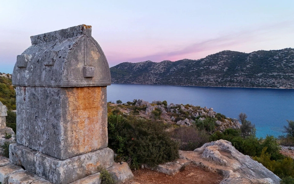 Ancient Lycian tomb along the walking path to Kaleköy (Simena) Castle in Kekova, Turkey, overlooking the bay at sunset.