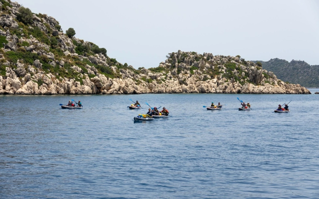 A group of people kayaking together during a Kekova sea kayak tour in Antalya, surrounded by rocky coastal scenery.
