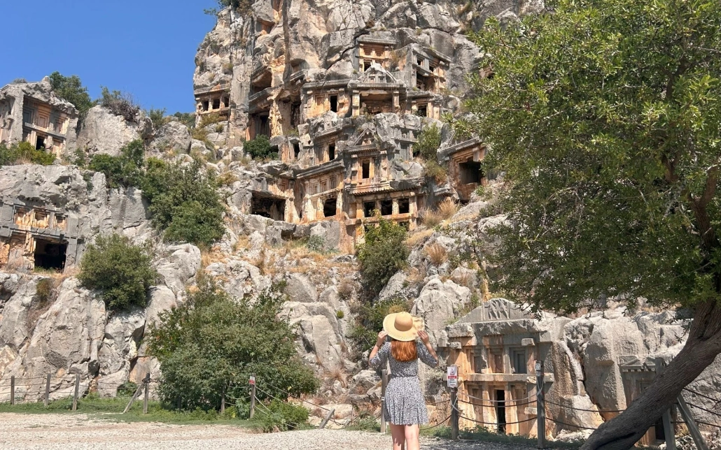 Female visitor standing in front of Lycian rock-cut tombs at Myra Ancient City, Demre.