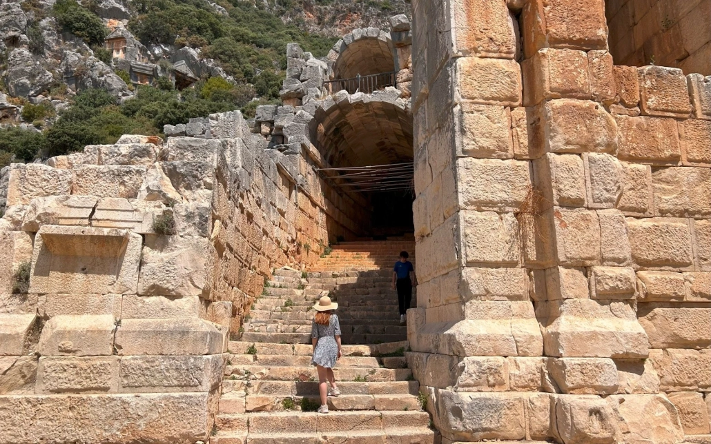 Female visitor near the rock tomb entrance and monumental ruins at Myra Ancient City.